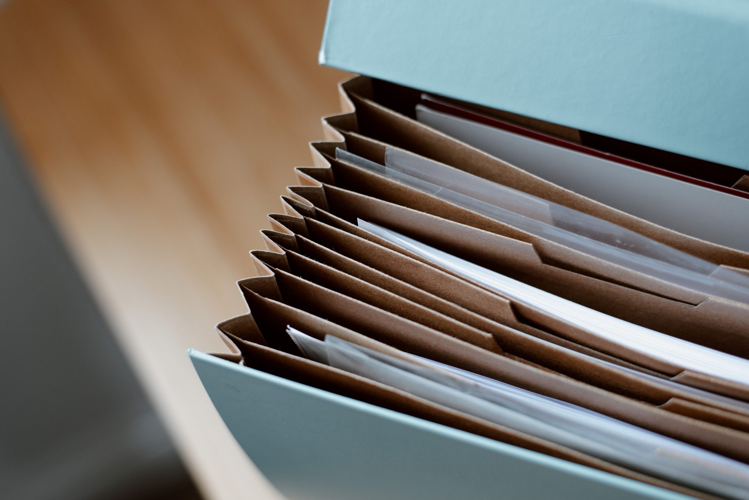 Color-coded file folders with a pen on a desk representing organized records